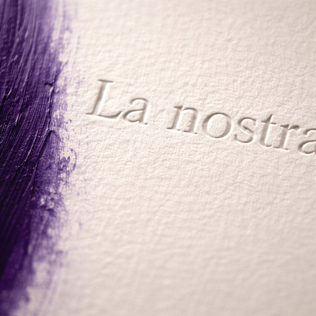 Dettaglio macro carta cotone con incisione tipografica e texture materica opaca